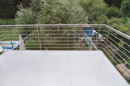 Balkongeländer in Edelstahl mit waagerechten Füllstäben an einem Balkon mit wunderschönem Ausblick in den Garten