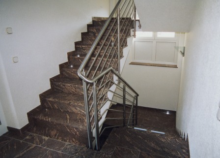 Geländer an Betontreppe als Metallgeländer mit einem gebogenem Handlauf in Edelstahl, Treppengeländer bieten Schutz gegen den Absturz