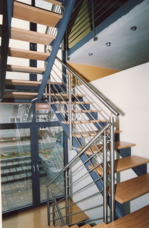 Podesttreppe als Metalltreppe mit Holzstufen, dieses Metallgeländer ist in Edelstahl und führt an der Galerie weiter als Brüstungsgeländer