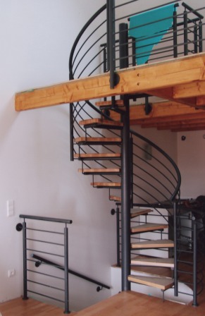 Spindeltreppe als Metalltreppe zum Obergeschoss, mit gebogenem Metallgeländer als Treppengeländer in Stahl