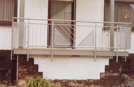 Balkongeländer in Edelstahl, mit Lochblech in Edelstahl und einem Edelstahlhandlauf an einem Balkon