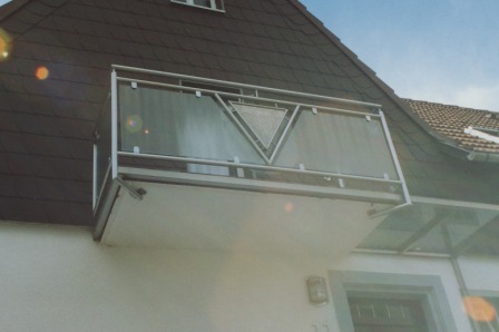 Balkongeländer in Edelstahl mit Glas an einem Betonbalkon mit einem Dreieck in der Mitte