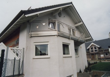 Balkongeländer in Edelstahl mit einer Blende in Edelstahl und Ornamenten an den senkrechten Stäben im Geländer