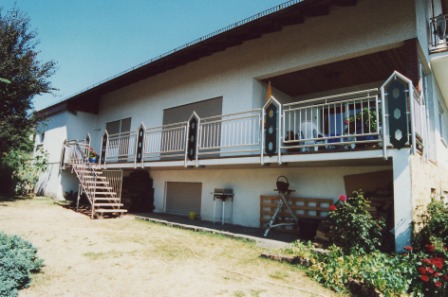 Balkongeländer in Edelstahl mit senkrechten Stäben und Ornamenten aus Lochblech, Außentreppe in den Garten