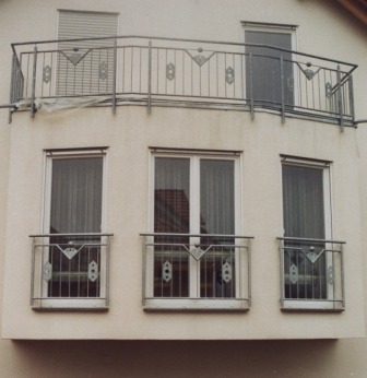Geländer verzinkt an einem Erker, als Balkongeländer sowie als Fenstergitter mit senkrechten Füllstäben und Ornamenten