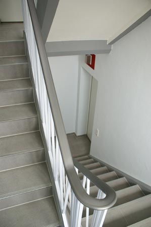 Handlauf aus Kunststoff nach Austausch und Neumontage in geschungenem Treppenhaus, hier in der Farbe Weißaluminium