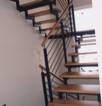 Innengeländer als Metallgeländer, dieses Treppengeländer ist an einer Zweiholmtreppe befestigt, diese Metalltreppe wurde als Podesttreppe ausgeführt, der Handlauf ist aus Holz