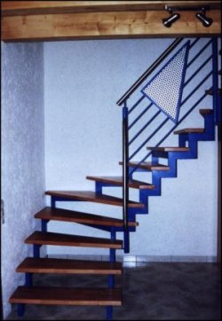 Innengeländer als Metallgeländer an einer Metalltreppe, dieses Treppengeländer besitzt blaue horizontale Füllstäbe sowie ein dreieckiges Ornament aus Lochblech