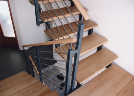 Innengeländer als Metallgeländer an einer Zweiholmtreppe, die Zweiholmtreppe ist als Metalltreppe ausgeführt, das Treppengeländer besitzt einen Holzhandlauf