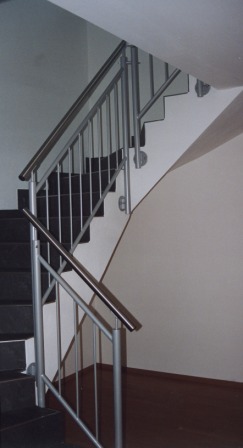 Stahlgeländer in drei Teilen an einer gewendelten Betontreppe, mit senkrechten Stäben als Treppengeländer