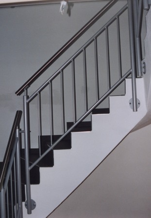 Stahlgeländer mit einem Handlauf in Edelstahl, senkrechten Stäben als Treppengeländer an einer gewendelten Betontreppe